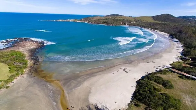 Vista aérea da baía da Praia do Rosa Norte, cercada por mata